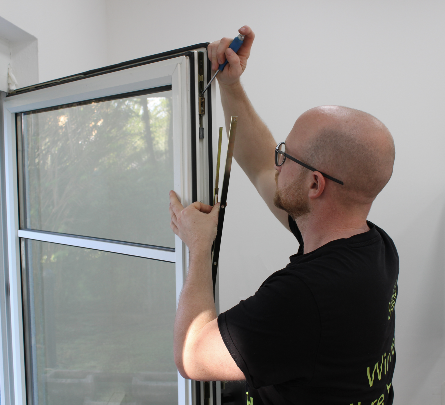 Das Bild zeigt einen Servicetechniker in Aktion, der sich auf die Reparatur und Wartung alter Fenster konzentriert und auch komplizierte Aufgaben bewältigen kann.